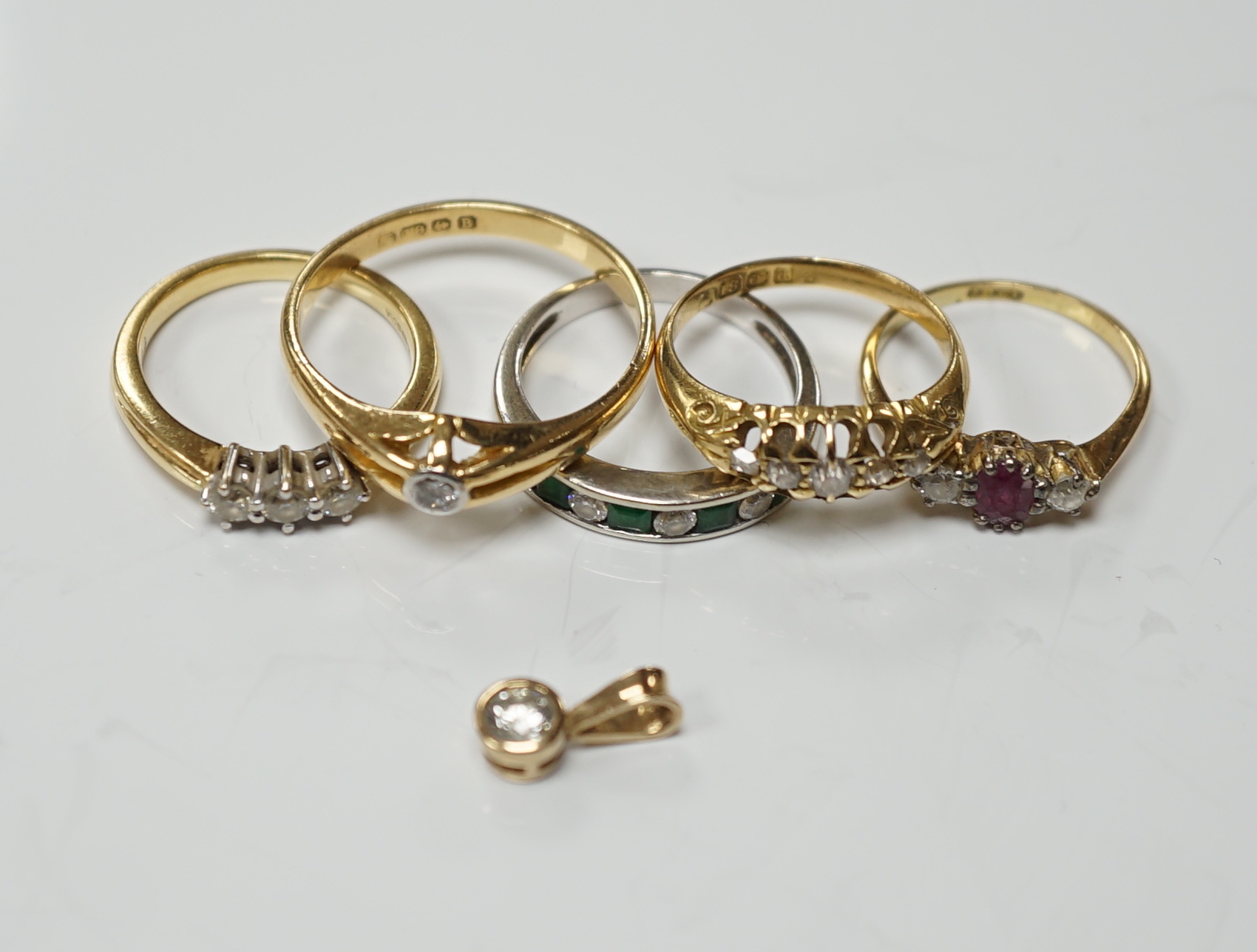 Four assorted early 20th century and later 18ct and gem set rings, including solitaire diamond and three stone diamond, gross 14.6 grams, together with a white metal and channel set emerald and diamond half hoop ring and